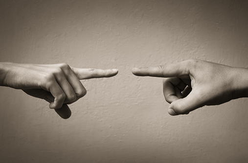 Photo by kieferpix on iStock of two hands pointing at each other, blaming each other.